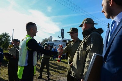 Berżniki. "Panie Komendancie, melduję wykonanie zadania" - kpt. SG Łukasz Lewczuk wręcza pałeczkę sztafetową Komendantowi Głównemu SG gen. bryg. SG Tomaszowi Pradze. (Podlaski OSG, 10.10.2018 g. 14.21)