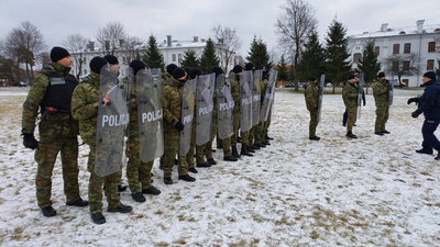 Funkcjonariusze stoją z tarczami ochronnymi 