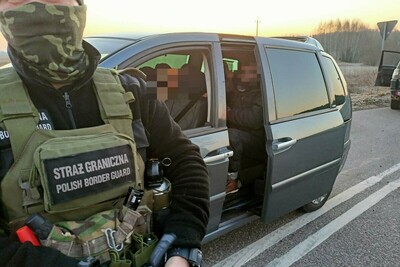 Funkcjonariusz Straży Granicznej z zatrzymanymi osobami 