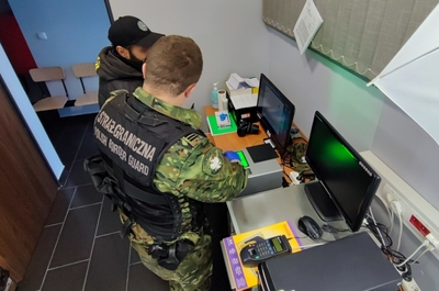 Funkcjonariusz SG pobiera odciski palców cudzoziemca 