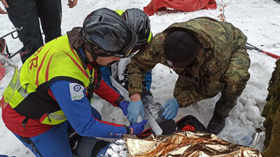 Funkcjonariusze SG, wspólnie z ratownikami GOPR-u, pomagają rannemu turyście 