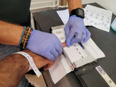 Funkcjonariusz SG pobiera odciski palców cudzoziemca 