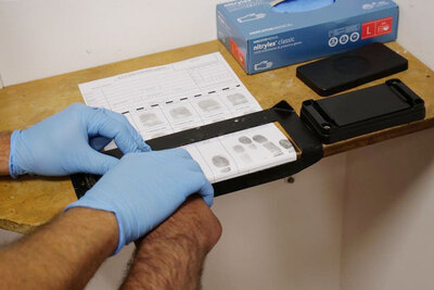 Funkcjonariusz SG pobiera odciski palców cudzoziemca 