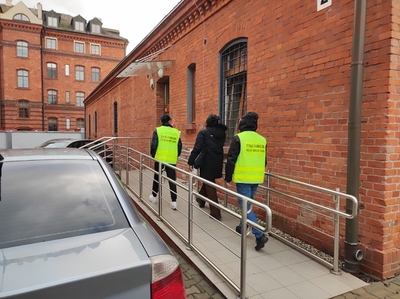 funkcjonariusze SG prowadzący osobę do pomieszczeń służbowych 