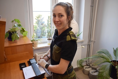 Funkcjonariuszka Straży Granicznej w czasie pobierania odcisków palców od cudzoziemca 