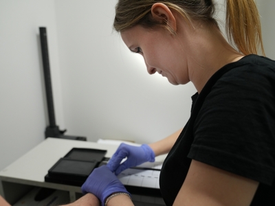 Funkcjonariuszka Straży Granicznej w czasie pobierania odcisków palców od cudzoziemca 