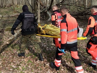 Funkcjonariusze wraz z ratownikami transportują cudzoziemca 