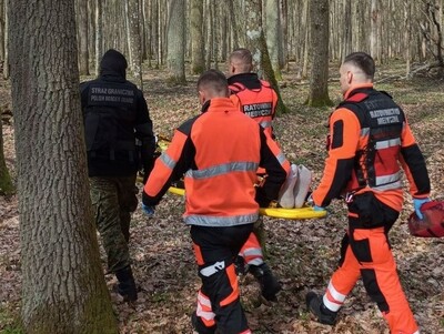 Funkcjonariusze wraz z ratownikami transportują cudzoziemca 