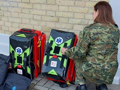 Funkcjonariuszka SG ogląda przekazane plecaki 