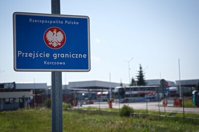 Tablica informacyjna, w tle przejście graniczne 