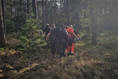 Funkcjonariusze SG i ratownicy medyczni podczas transportu poszkodowanego 
