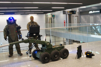 Funkcjonariusz w kombinezonie antywybuchowym i robot pirotechniczny Funkcjonariusz w kombinezonie antywybuchowym i robot pirotechniczny