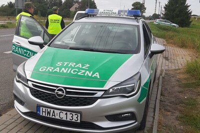 Funkcjonariusze SG przy pojeździe służbowym 