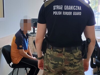 Funkcjonariusz SG stoi przy zatrzymanym Funkcjonariusz SG stoi przy zatrzymanym