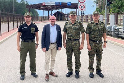 Wiceminister SWiA, Zastępca Komendanta Głównego SG, Komendant Podlaskiego Oddziału SG stoją tle infrastruktury przejścia granicznego Wiceminister SWiA, Zastępca Komendanta Głównego SG, Komendant Podlaskiego Oddziału SG stoją tle infrastruktury przejścia granicznego