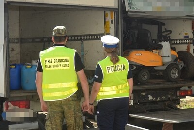 Funkcjonariusz Straży Granicznej i funkcjonariuszka Policji stoją obok pojazdów Funkcjonariusz Straży Granicznej i funkcjonariuszka Policji stoją obok pojazdów