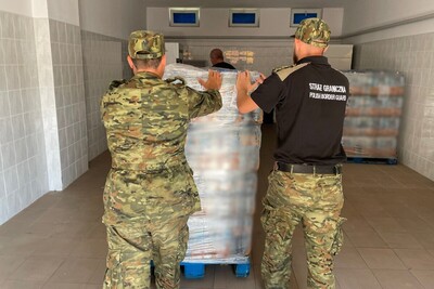 Dwóch funkcjonariuszy Straży Granicznej przy palecie z produktami spożywczymi Dwóch funkcjonariuszy Straży Granicznej przy palecie z produktami spożywczymi