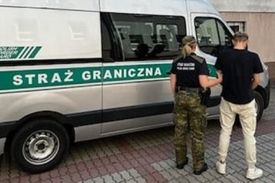 Funkcjonariuszka Straży Granicznej z zatrzymanym stoją przy pojeździe służbowym Straży Granicznej Funkcjonariuszka Straży Granicznej z zatrzymanym stoją przy pojeździe służbowym Straży Granicznej
