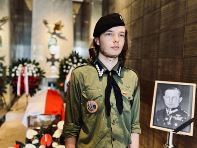 Harcerz stojący obok zdjęcia gen. Kruszewskiego, w tle trumna z flagą państwową Harcerz stojący obok zdjęcia gen. Kruszewskiego, w tle trumna z flagą państwową