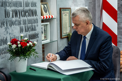 Minister Spraw Wewnętrznych i Administracji wpisuje się do księgi pamiątkowej.ej Minister Spraw Wewnętrznych i Administracji wpisuje się do księgi pamiątkowej.