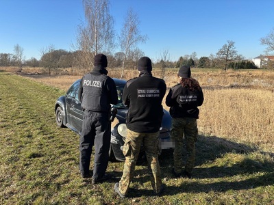 Funkcjonariusze wspólnego polsko-niemieckiego patrolu stoją przy zatrzymanym samochodzie Funkcjonariusze wspólnego polsko-niemieckiego patrolu stoją przy zatrzymanym samochodzie