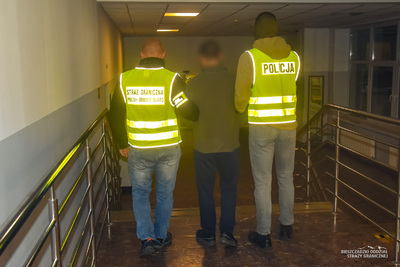 Zatrzymany mężczyzna z funkcjonariuszami Straży Granicznej i Policji 