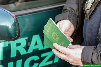 Funkcjonariusz Straży Granicznej trzyma wietnamskie paszporty Funkcjonariusz Straży Granicznej trzyma wietnamskie paszporty