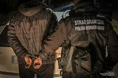 Funkcjonariusz Straży Granicznej prowadzi zatrzymanego Funkcjonariusz Straży Granicznej prowadzi zatrzymanego