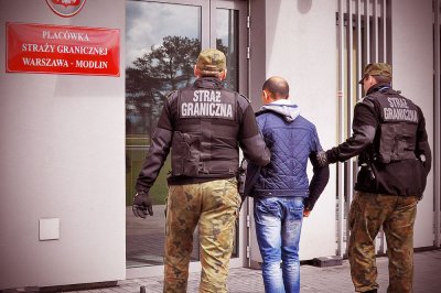 zatrzymany mężczyzna prowadzony przez funkcjonariuszy SG 